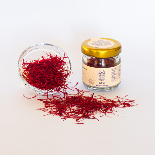 Kangina 2 g glass jar beside a tipped bowl spilling vivid red threads on a white background