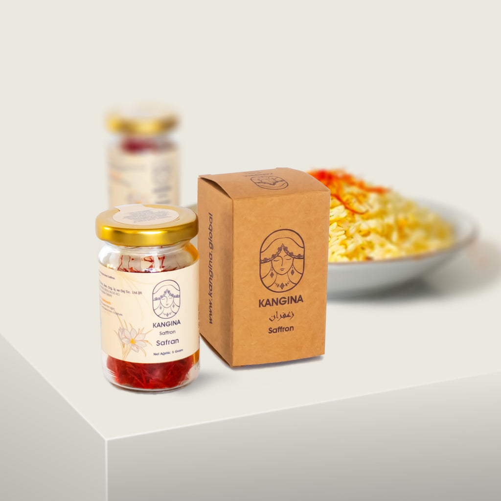Kangina premium Afghan saffron threads jar and branded kraft box on white plinth with a blurred dish of yellow saffron rice in the background