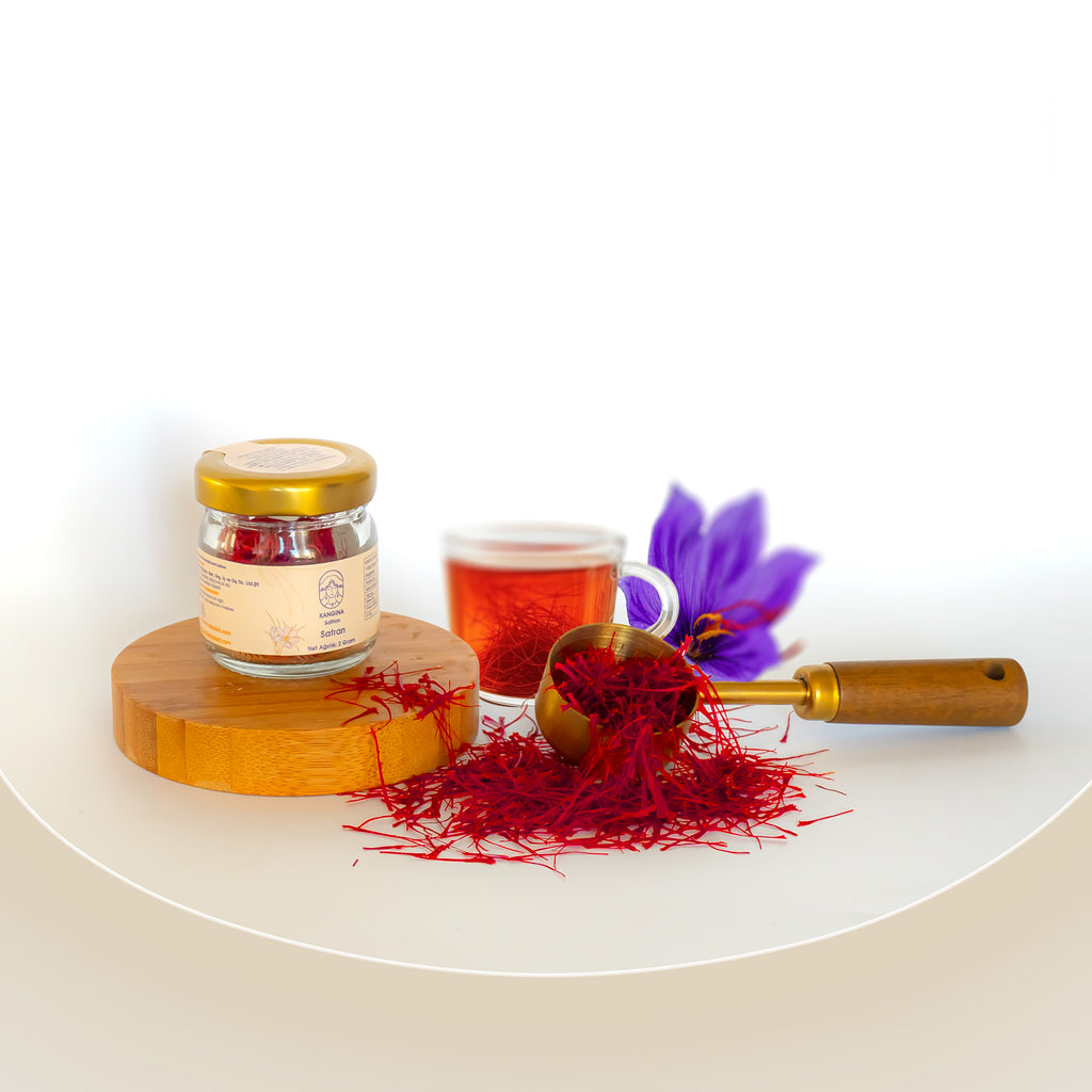 Kangina premium Afghan saffron threads styled composition of Kangina saffron jar on wood pedestal with saffron crocus flower, tea cup and scattered threads