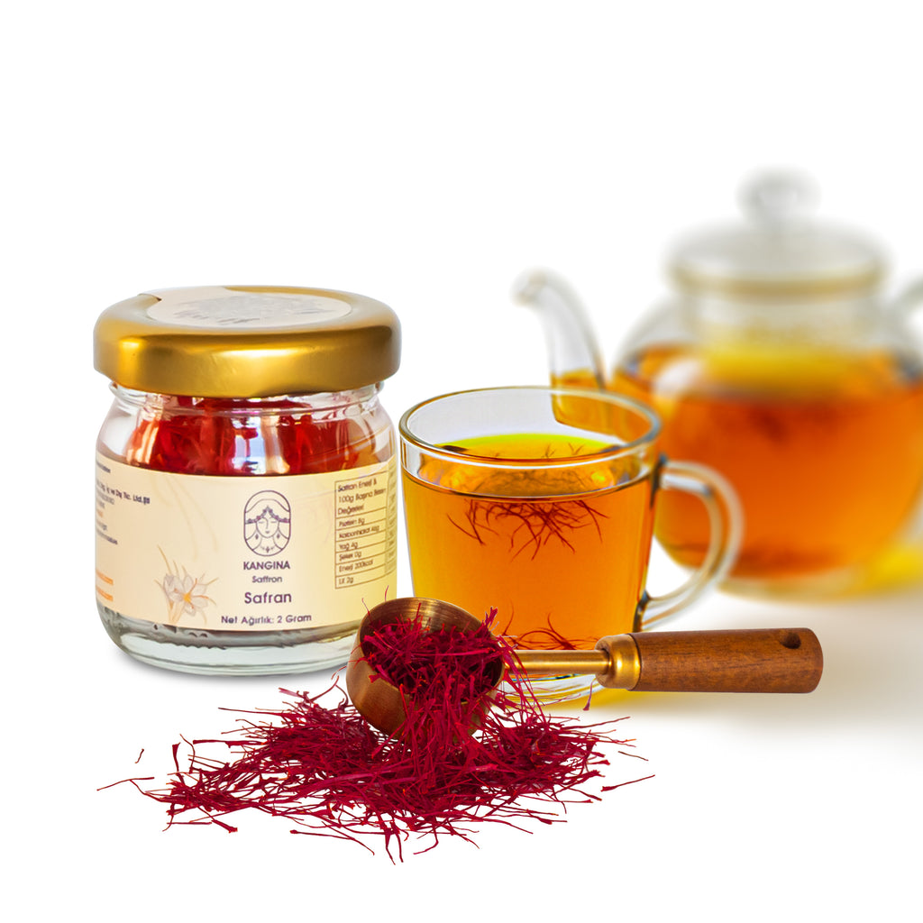 Kangina premium Afghan saffron threads lifestyle scene: Kangina saffron jar, wooden scoop, loose threads and a clear cup of brewed saffron tea with teapot behind